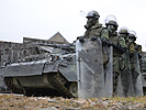 Panzergrenadiere mit Schutzschildern neben einem Schützenpanzer